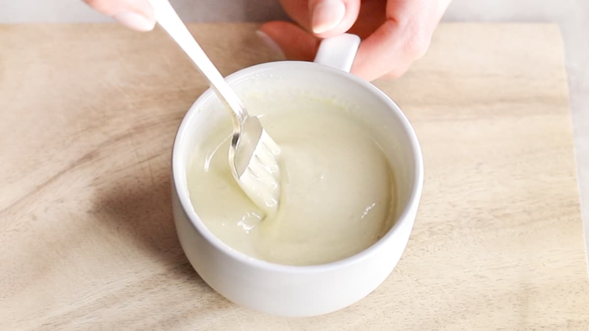 Wasabi dressing being whisked with a fork in a mug