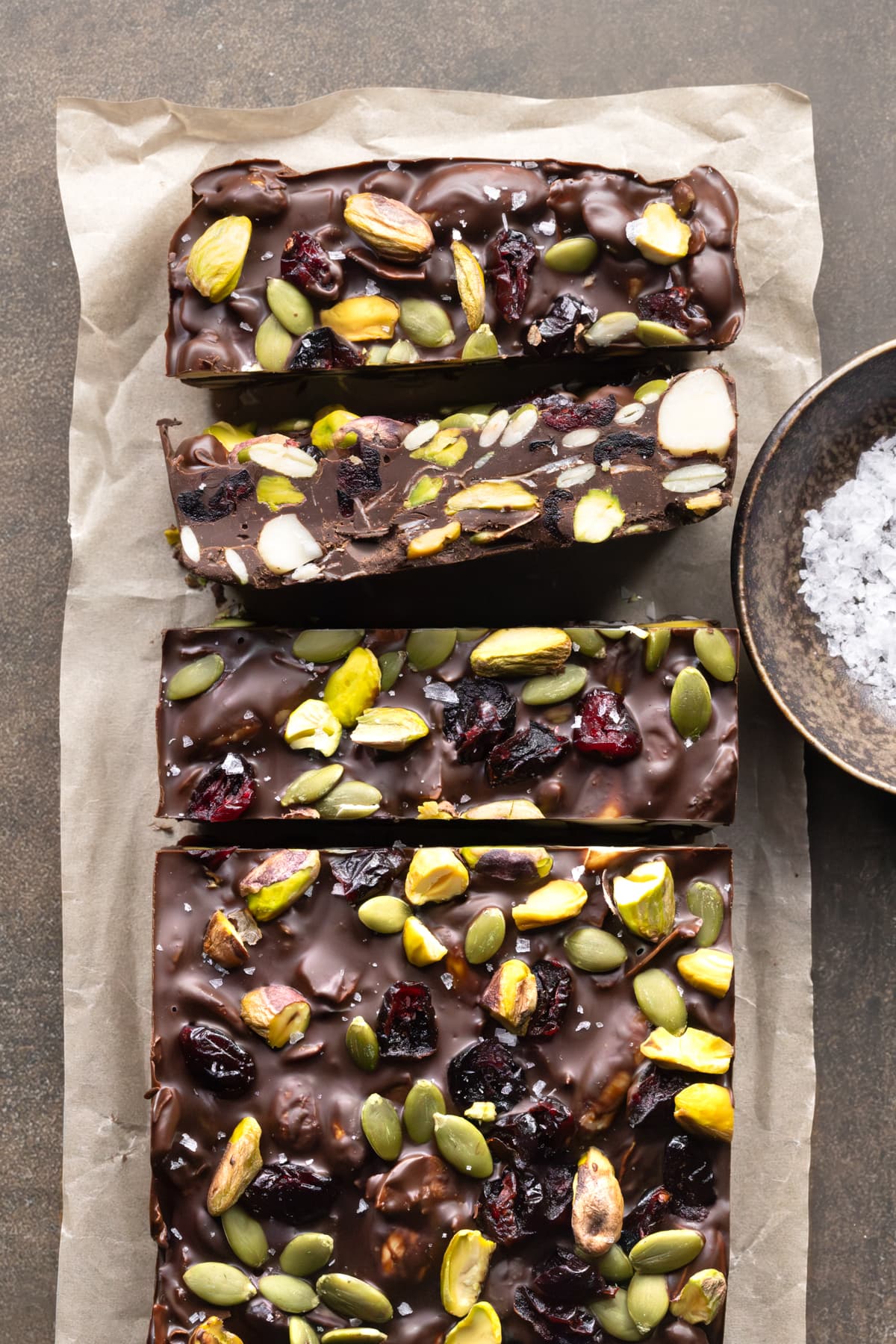 A slab of rocky road made with dark chocolate, cut into bars and arranged on parchment paper