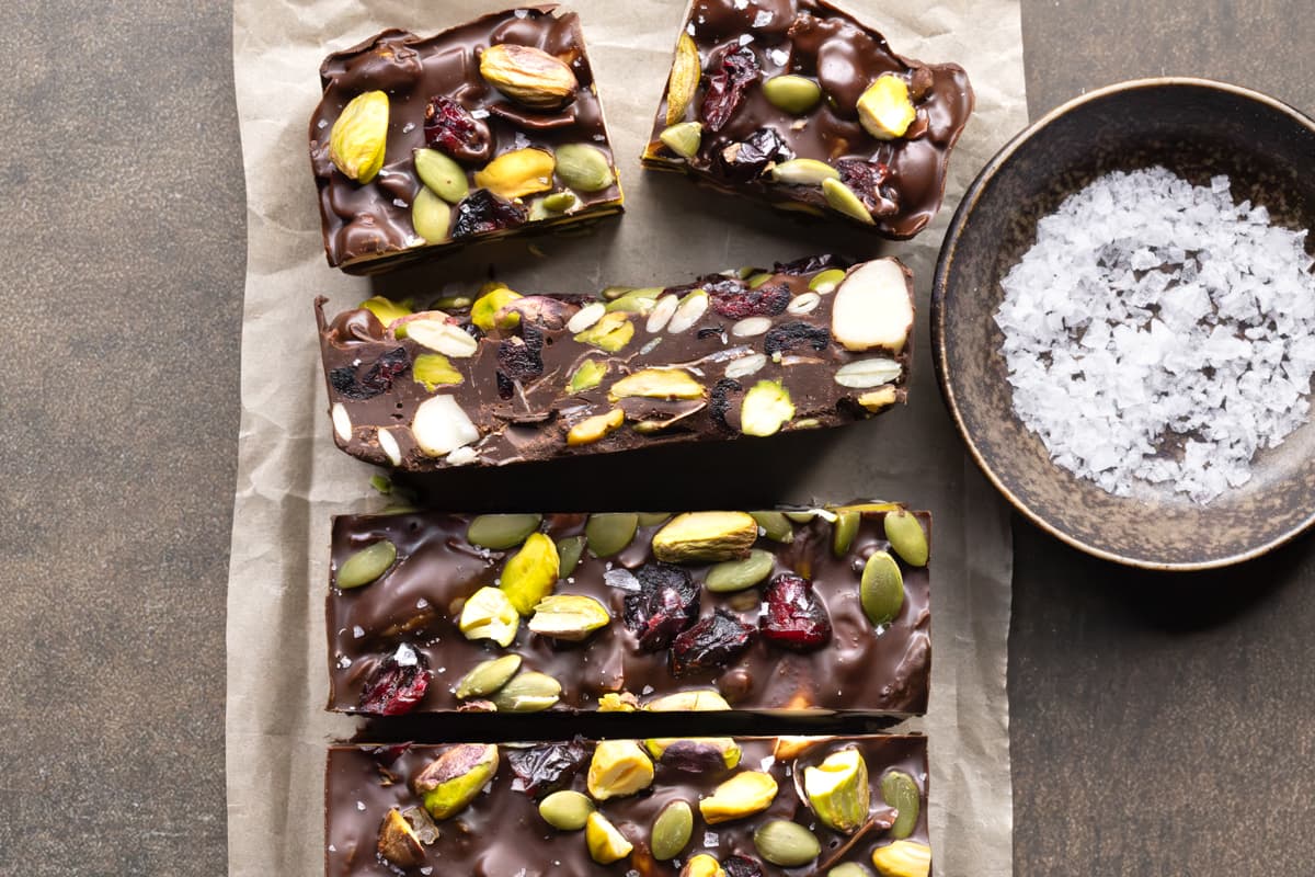 Dark chocolate rocky road pieces with nuts and dried fruit, served beside a small bowl of flaky sea salt