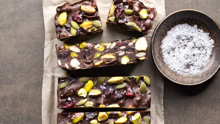 Dark chocolate rocky road bars with nuts, dried fruit, and coconut, served with a bowl of sea salt flakes