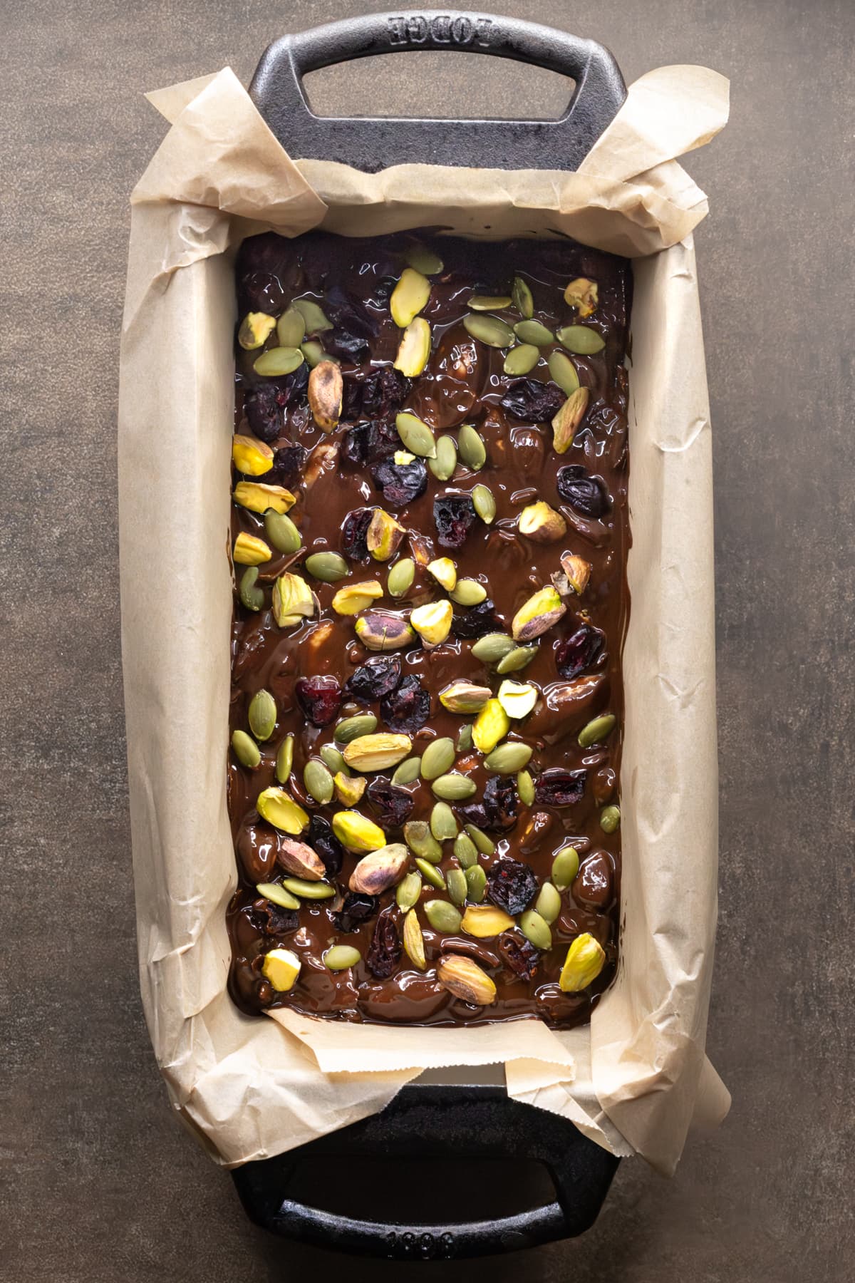 Rocky road mixture with nuts, dried fruit, and coconut pressed into a parchment-lined loaf pan before chilling