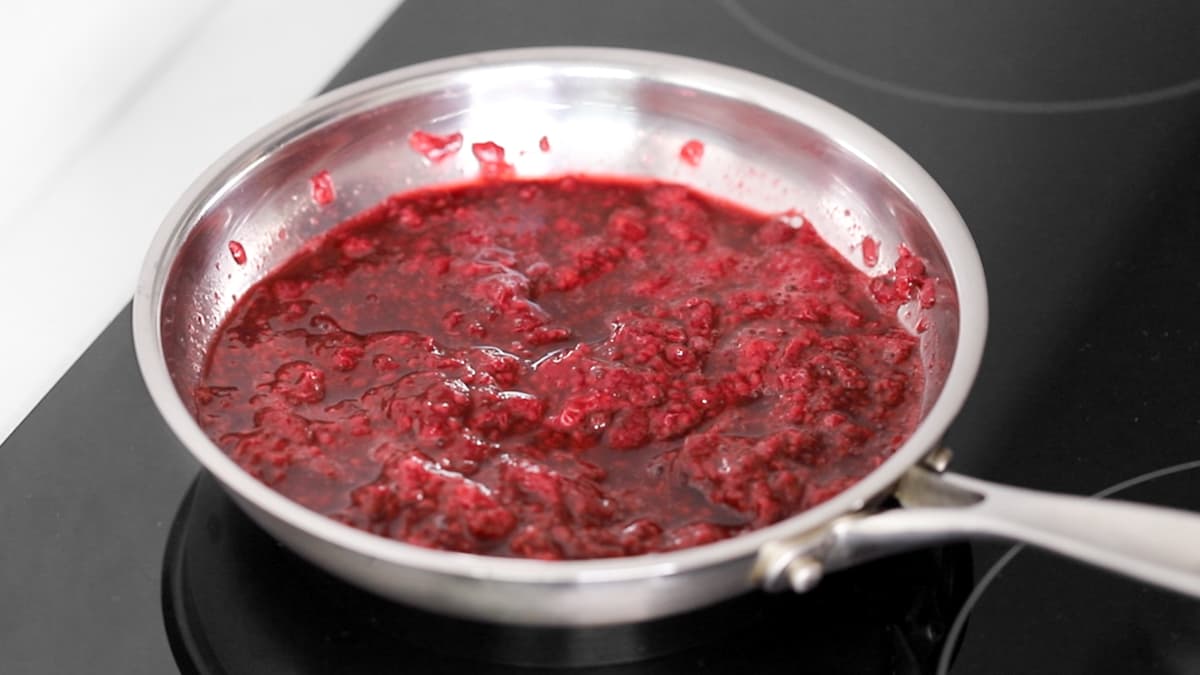 Softened and mashed raspberries in a saucepan for homemade raspberry compote