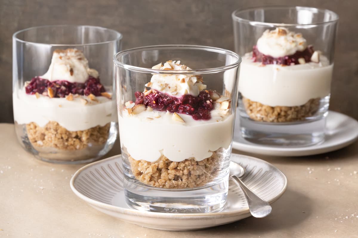 Three no-bake cheesecake cups with raspberry compote and almond topping