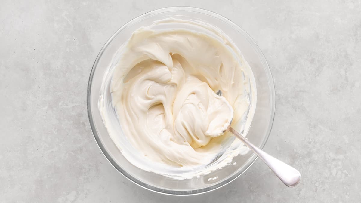 Creamy no-bake cheesecake filling mixture in a bowl with a spoon