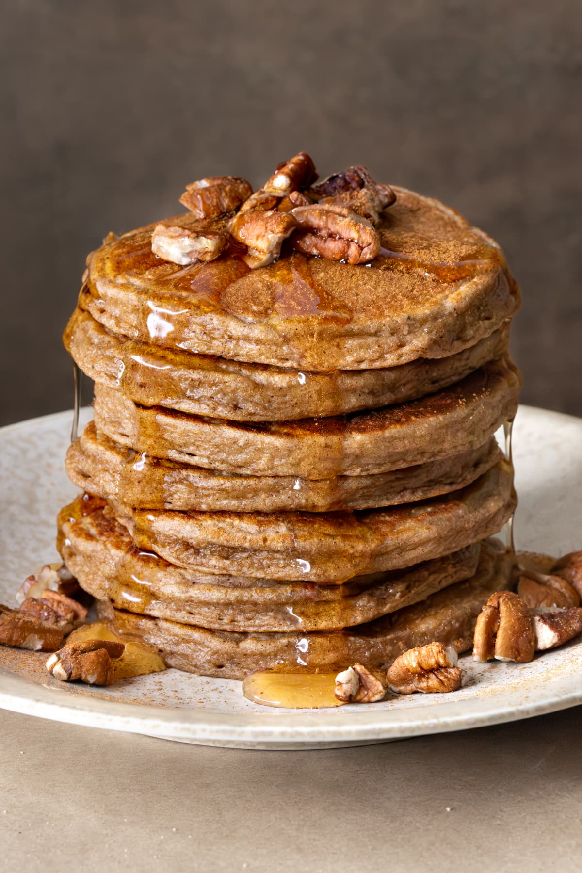 A stack of pancakes topped with chopped pecans and brown rice syrup