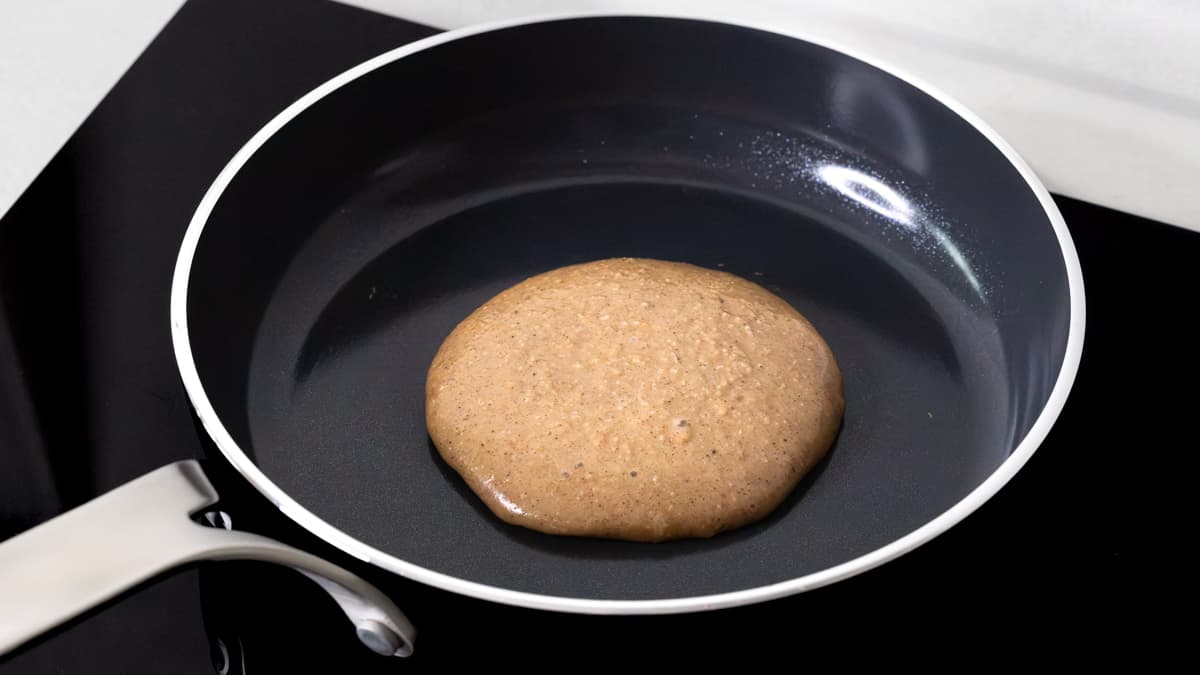 A portion of banana cottage cheese pancake batter cooking in a frying pan