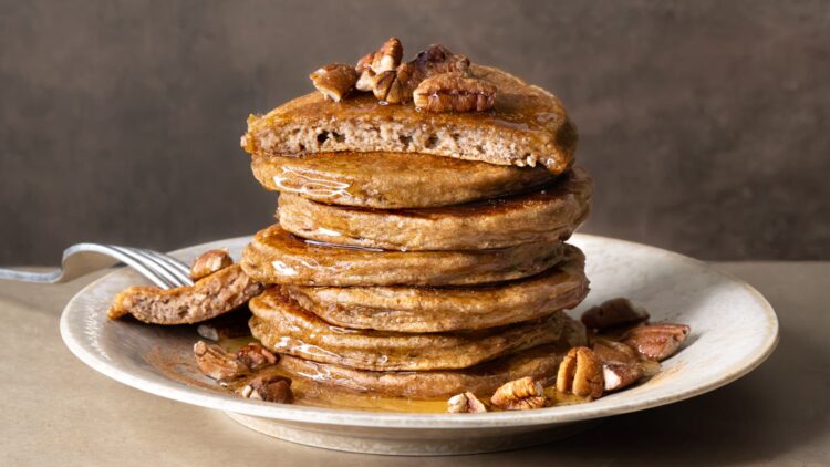 A stack of cottage cheese banana pancakes with the top pancake cut in half