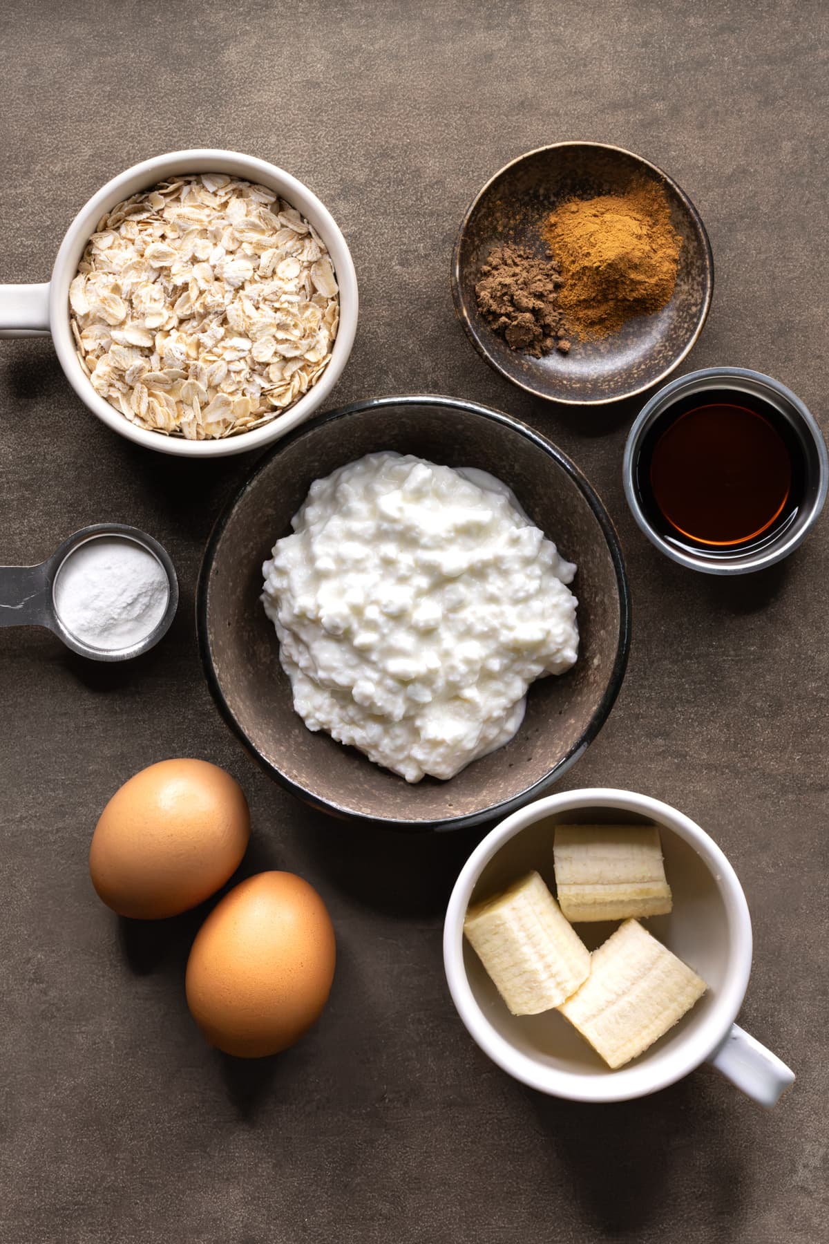 Ingredients for cottage cheese banana pancakes set out in bowls and cups