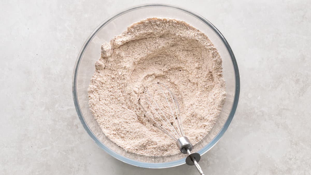 Dry ingredients for pumpkin oat muffins mixed in a bowl with a whisk