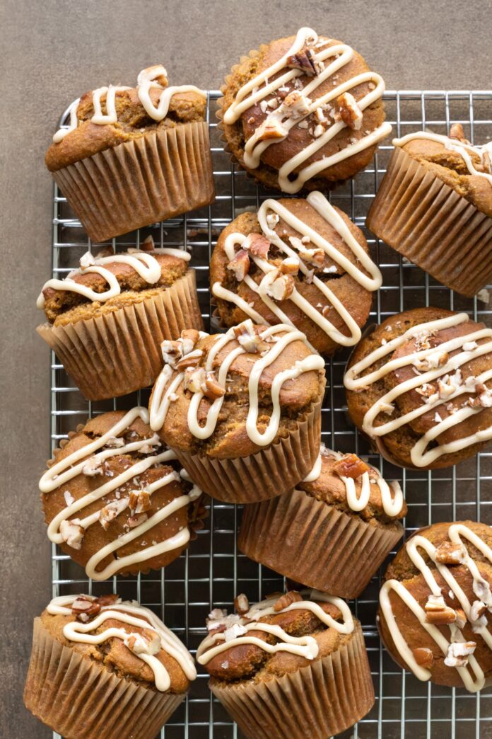 Pumpkin oatmeal muffins topped with maple glaze and pecans arranged on a cooling rack