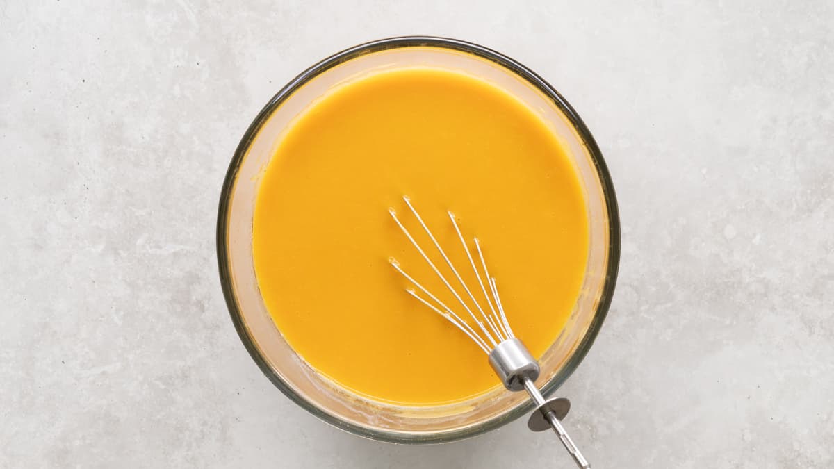 Wet ingredients for pumpkin oatmeal muffins mixed in a bowl with a whisk
